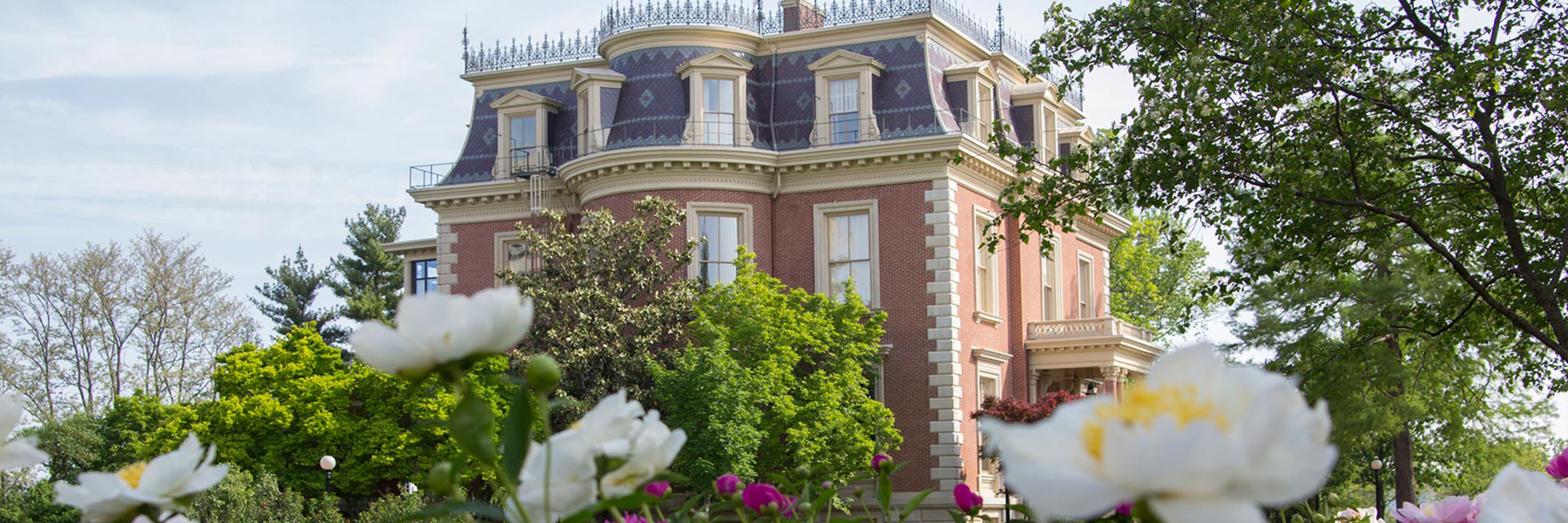 Mansion in the spring with peonies in the foreground